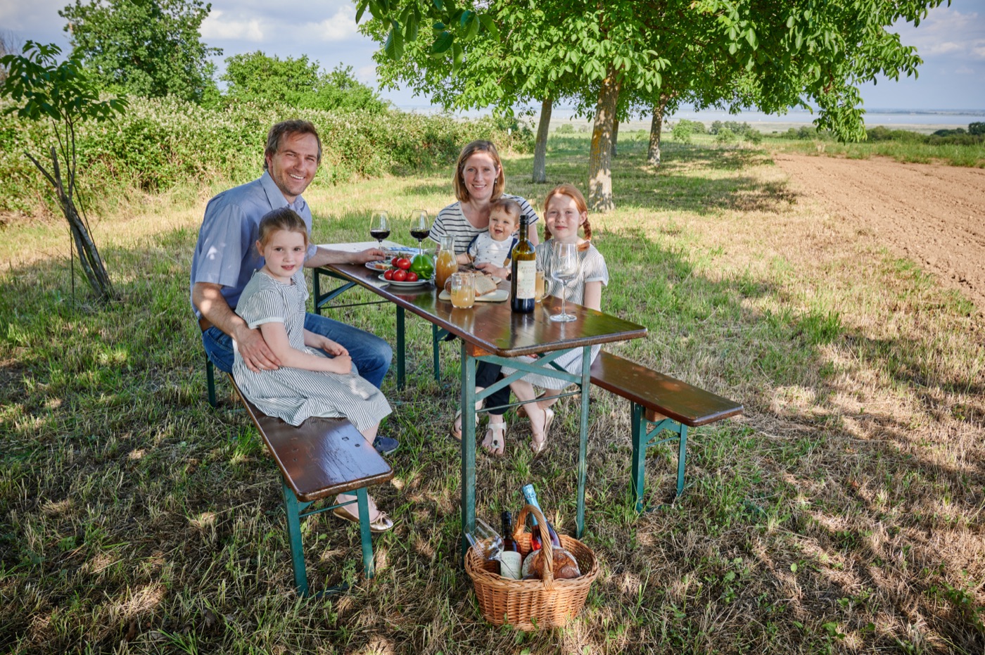 Familie am Picknicktisch unter Nussbäumen